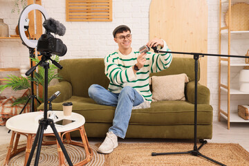 Young man on sofa with microphone recording podcast in studio