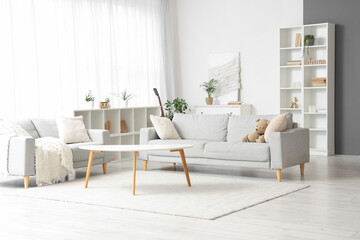 Interior of light living room with grey sofas, table and shelf units