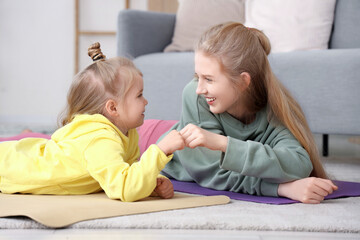 Sporty little girl with her mother bumping fists at home