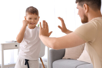 Young man and his little son boxing in living room