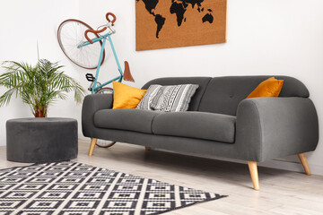 Interior of cozy living room with sofa, bicycle and map near white wall