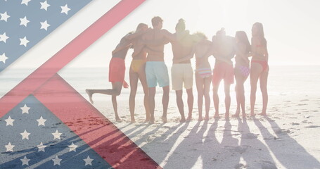 Image of american flag over diverse group of friends embracing at beach