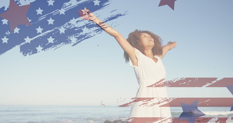Image of american flag over african american woman raising hands at beach