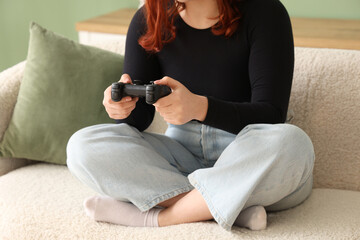 Young woman playing video game on sofa at home, closeup