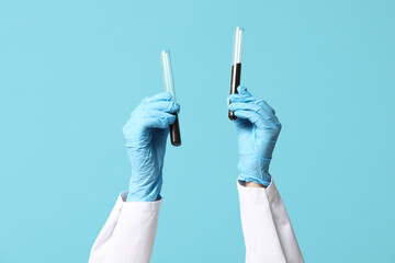 Scientist's hands holding test tubes with soil on blue background