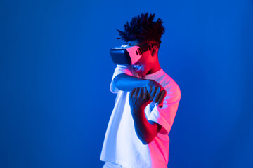 Young African American player wearing VR playing sword or baseball hologram isolated blue pink neon...