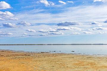 Scenic summer landscape blue sky clouds, water surface and sandy shore. Minimal aesthetic nature...