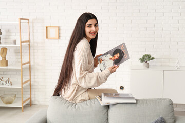 Beautiful young happy woman with different magazines at home