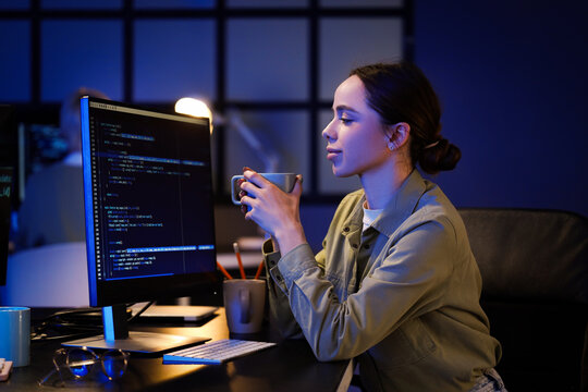 Female programmer with coffee cup sitting in office at night