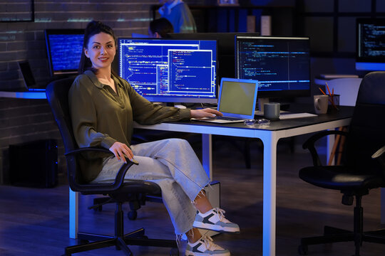 Female programmer working with laptop in office at night
