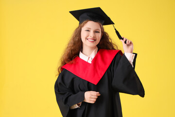 Happy female graduating student on yellow background