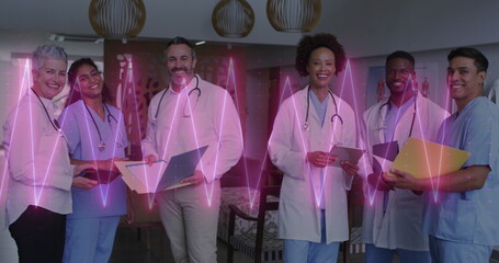 Image of heart rate monitor over team of diverse doctors and health workers smiling at hospital