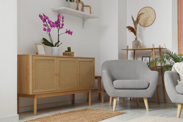 Interior of living room with wooden commode and armchair