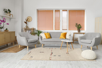 Interior of living room with wooden commode, sofa and armchairs