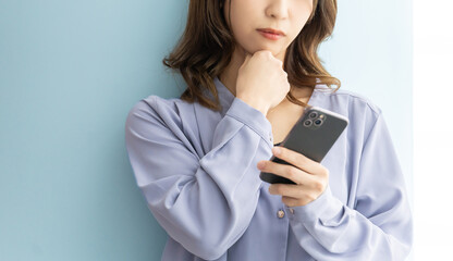 スマートフォンを見て真剣な表情で考える日本人女性
