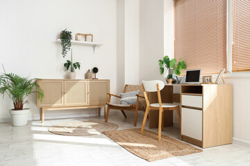 Interior of light office with workplace, drawers and green houseplants