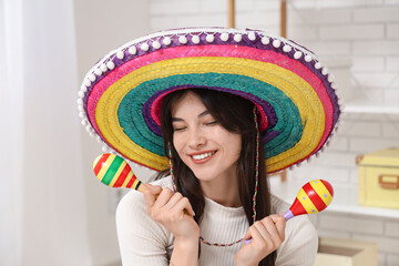 Young woman in sombrero with maracas at home. Cinco de Mayo celebration