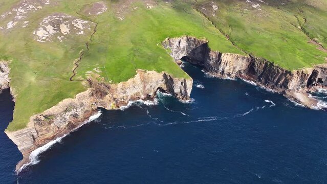 Aerial View of Steep Cliffs Above Sea and Green Pastures on Coastline of Scotland UK