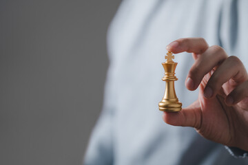 Businessman hand holding golden king chess for business strategy and leadership assignment...