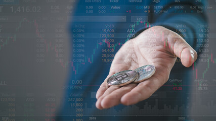 Hand holding Bitcoin trading chart on the screen. Holding in hand a Bitcoin Cash coin. Trading on...