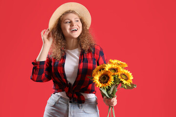 Happy young woman with sunflowers and straw hat on red background. Festa Junina celebration