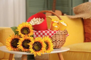 Wicket basket with popcorn and sunflowers on coffee table in living room. Festa Junina celebration