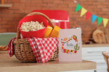 Wicket basket with popcorn and greeting card on table in kitchen. Festa Junina celebration