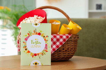 Wicket basket with popcorn and greeting card on coffee table in living room. Festa Junina...