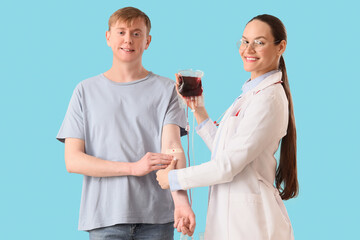 Male donor giving blood with doctor on blue background