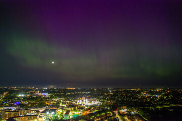 An aerial view of the Aurora Borealis over Cleveland, Ohio on May 5th, 2024. The Northern Lights are green near the horizon but became purple higher up and part of the city is visible.