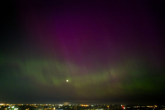 An aerial view of the Aurora Borealis over Cleveland, Ohio on May 5th, 2024. The moon hides behind a green glow the turns bright purple