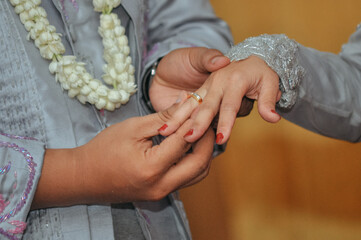 closeup of the groom's finger putting the ring on the bride