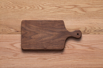 Handmade black walnut wood cutting board on oak tabletop. Wooden cutting board.