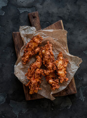 Deep-fried chicken breast pieces in batter - delicious snack, tapas on a cutting board on a dark...