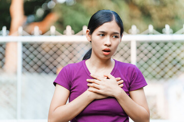 A young Asian woman appears panicked outside her home. She exhibits signs of anxiety, fear, and...