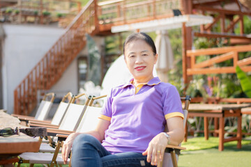 Portrait of mid adult asian woman sitting outside of her house, soft focus, happiness of humans...