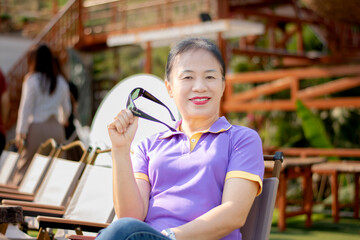 Portrait of mid adult asian woman sitting outside of her house, soft focus, happiness of humans...