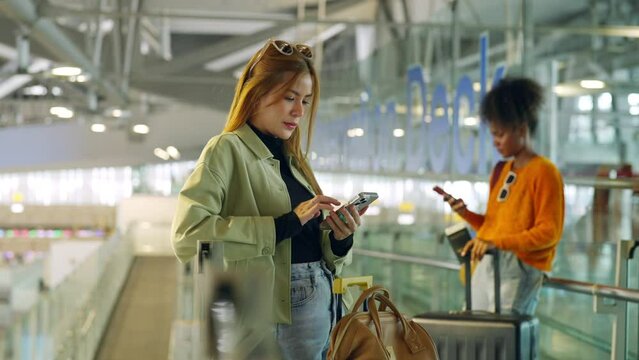 Young woman passengers using mobile phone booking hotel or online remote working during waiting flight at boarding in airport terminal. Attractive girl tourist travel by airplane on holiday vacation.