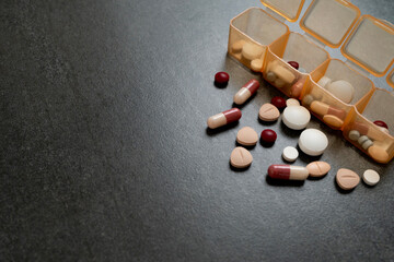 many colorful drug medicines or pill  in a pillbox on teh table healthy and medicine concept