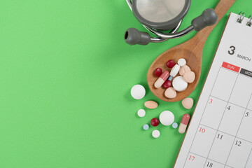 many colorful drug medicines or pill and calendar on the green table background, healthy and medicine concept