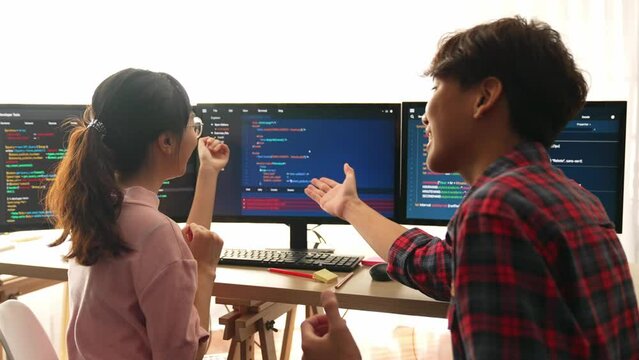 Slow motion back end software developer engineer for computer programming working together on debugging writing computing code, solving complex algorithms display on monitor in office. Burgeoning