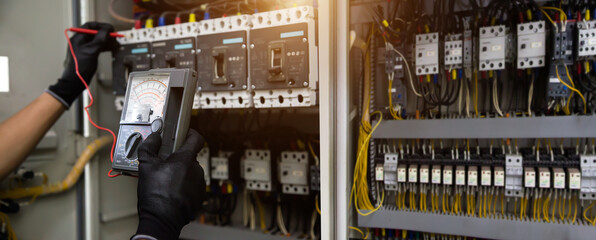Electrician use electrical measuring tool meter at main panel circuit breaker power electricity switchboard system cabinet for repairing or safety service maintenance and electric cable wiring check.