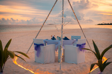 Idyllic table setup wedding ceremony on sunset beach. Romantic destination dining, couple...