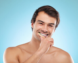Portrait, brushing teeth and man with dental hygiene, wellness and grooming routine on blue studio...