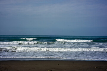 powerful foamy sea waves rolling and splashing over water surface against cloudy blue sky