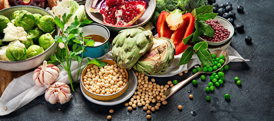 Vegan food. Pepper, broccoli, cabbage, garlic, mushrooms, pomegranate on a dark background