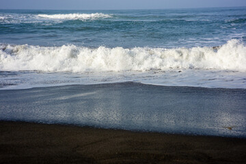 powerful foamy sea waves rolling and splashing over water surface against cloudy blue sky