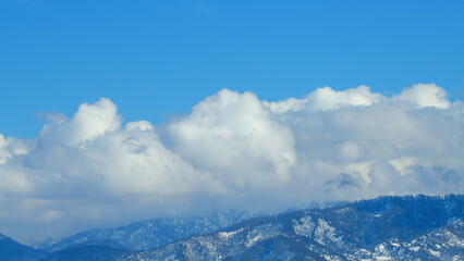 Mountains With Clouds Running Opposite Direction On Blue Sky. Snow-Covered Hills Of Mountains....