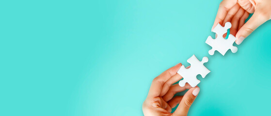 Two hands connecting puzzle pieces, on a solid turquoise background, representing the concept of solution or teamwork. Generative AI