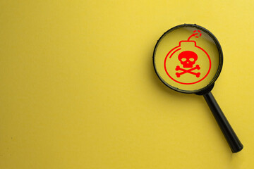 Magnifying glass focus on red bomb and skull icon on yellow background meaning for Attention,Warning sign,Security and Safety,Danger or Threat.